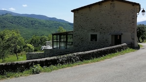 A stone building with a sloped roof, a small window, and a door. - The barn corner of paradise (Leychert)