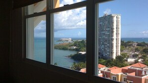 A view from a window overlooking a coastal area with a tall building, a body of water, and a small island. - The best vacation in Puerto Rico (Fajardo)