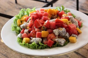 En skål med frugtsalat bestående af vandmelon, mango og dragefrugt på en bund af salat.
