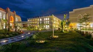 Un patio de hotel con un sendero central, rodeado de abundante vegetación e iluminado con luz ambiental.