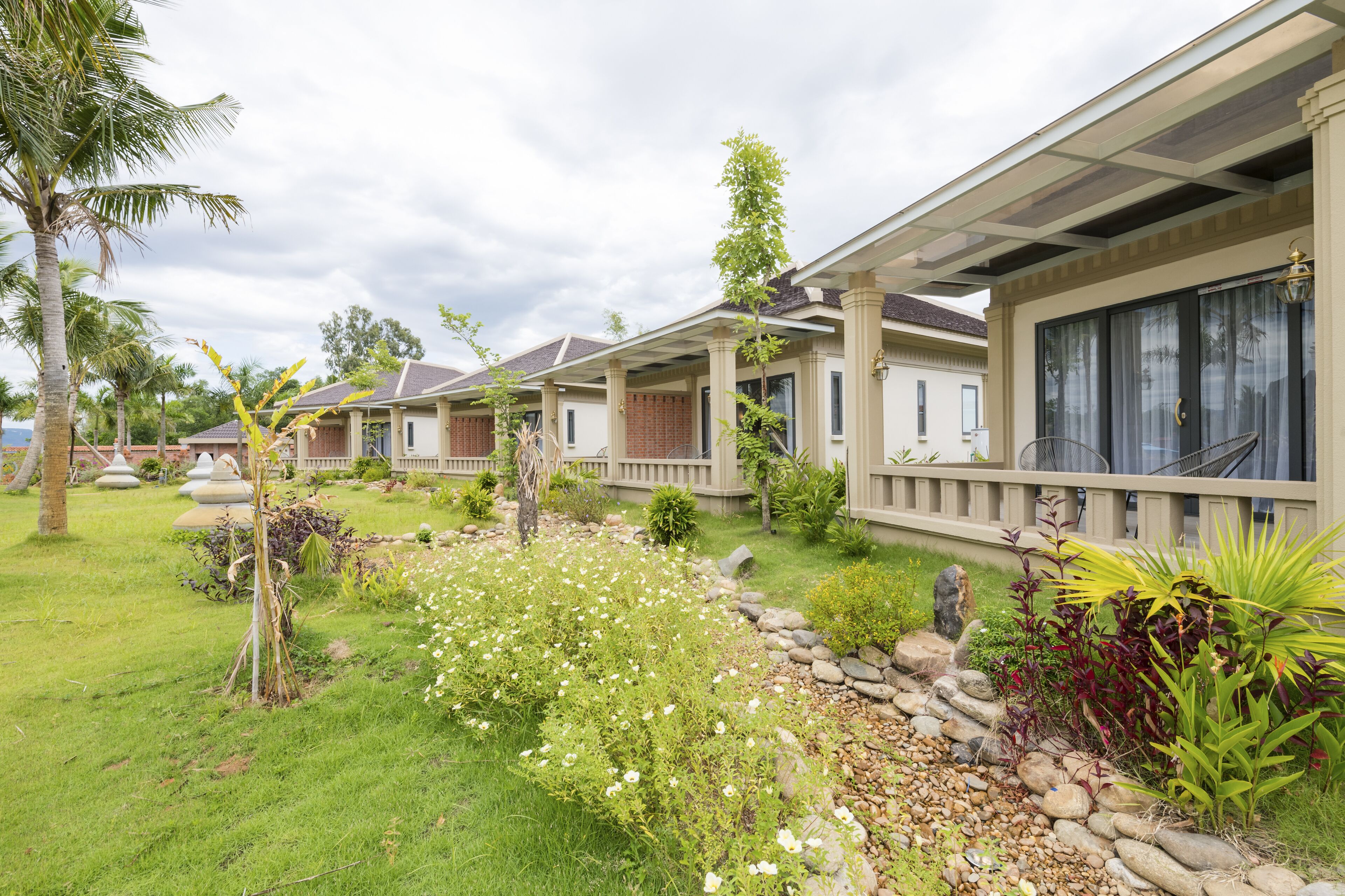 A row of houses with a well-maintained garden, including a grassy area and various plants.