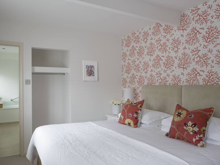 A bedroom with a bed, pillows, a nightstand, a wall-mounted shelf, and a framed picture.