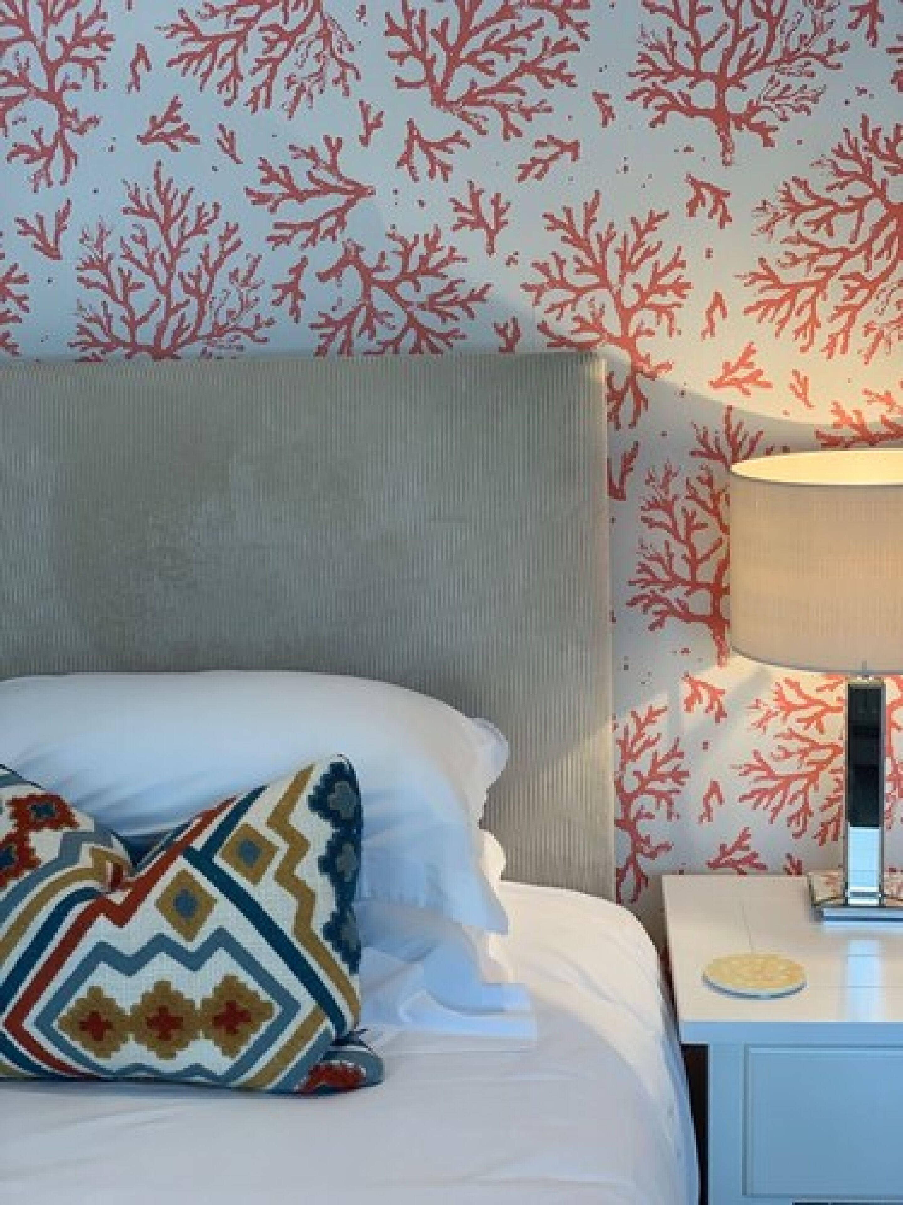 Ein Hotelzimmer mit einem Bett, einem Nachttisch und einer Wand mit Korallenmuster-Tapete.