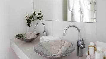 A bathroom with a marble sink, a mirror, and a towel rack.