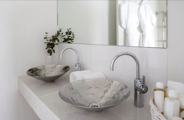 A bathroom with a marble sink, a mirror, and a towel rack. - Boskerris Hotel (St Ives)