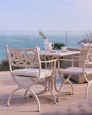 A white outdoor dining set with a view of the ocean. - Boskerris Hotel (St Ives)