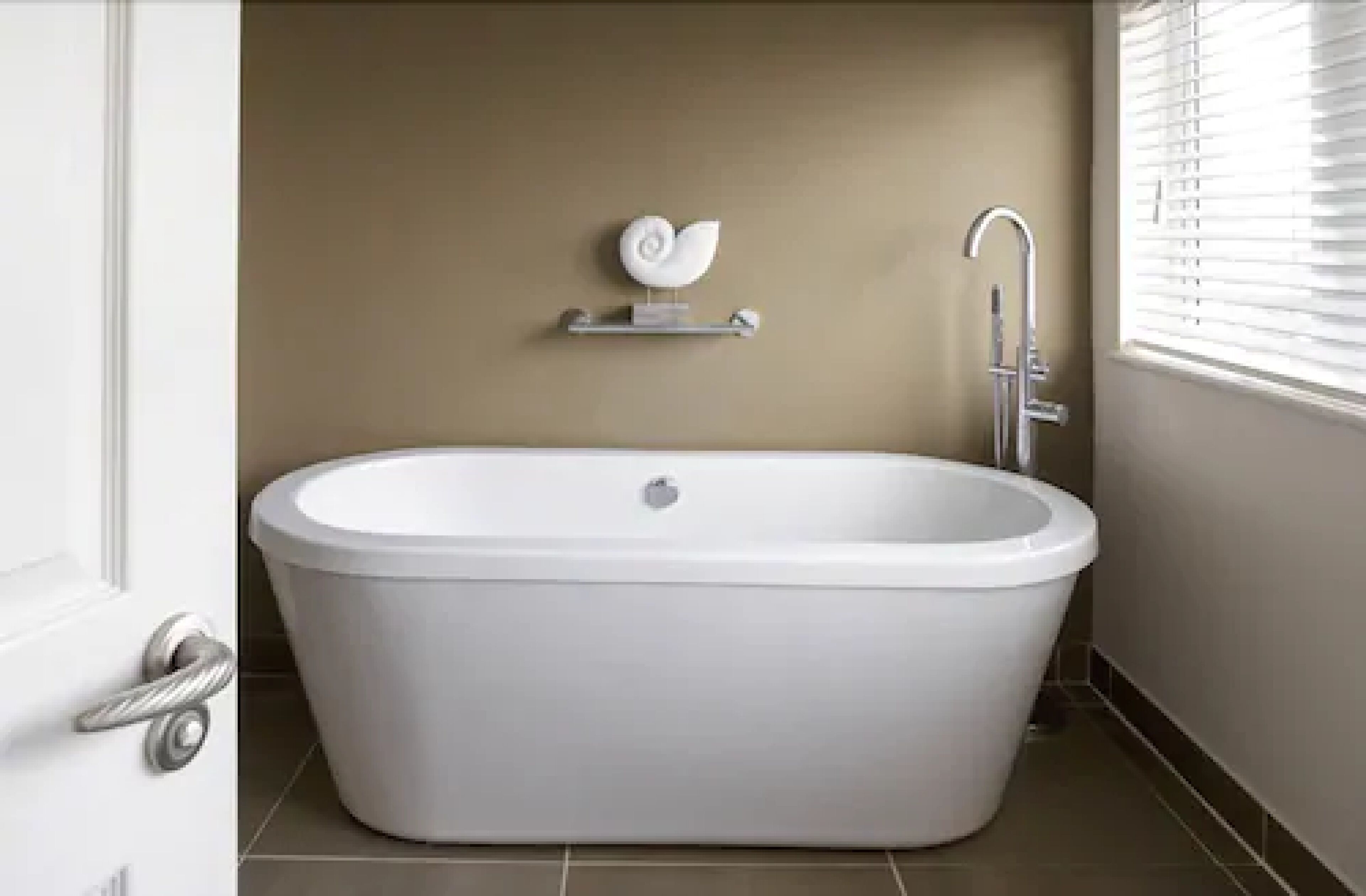 A bathroom with a freestanding bathtub, a towel rack with a towel, and a showerhead.
