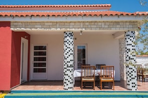 A covered outdoor seating area with a table and chairs, a tiled roof, and a pool in the foreground. - VILLA CROATIA in the quiet village of CISTA VELIKA in the countryside (Cista Velika - Vodice)