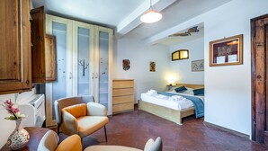 Un dormitorio con cama, una silla, cómoda y armario.