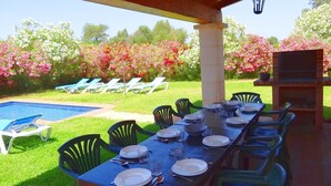 An outdoor dining area with a pool, lounge chairs, and a grill.
