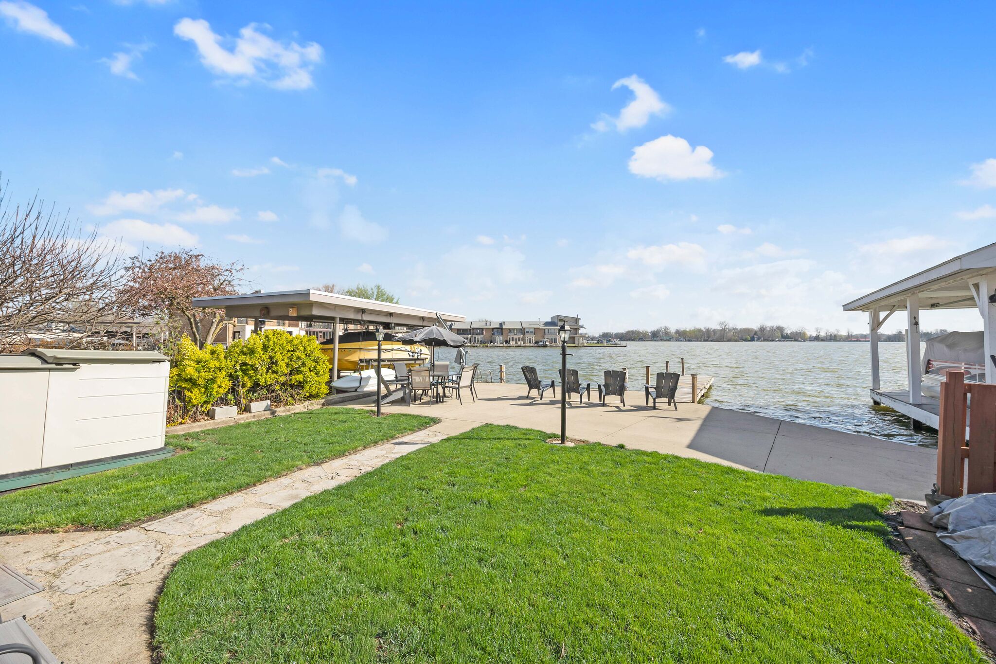 Ein Anwesen am Seeufer mit Terrasse, Gartenmöbeln und Bootsanleger.
