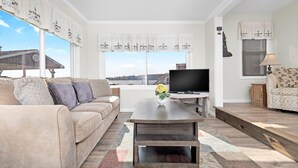 A living room with a sofa, a coffee table, a TV, and a window with curtains.