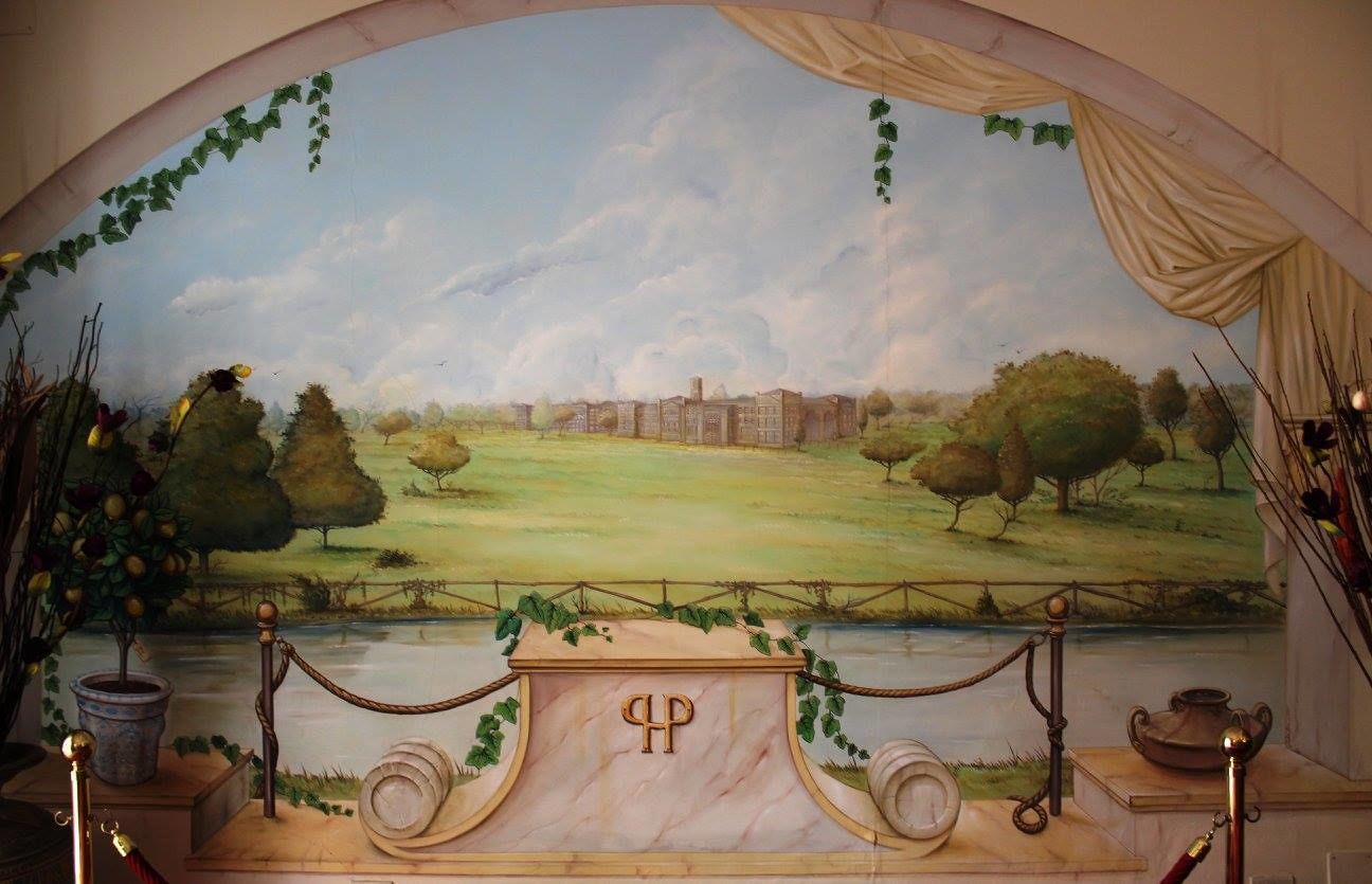 Un mural que muestra un paisaje con un edificio, árboles y un río.