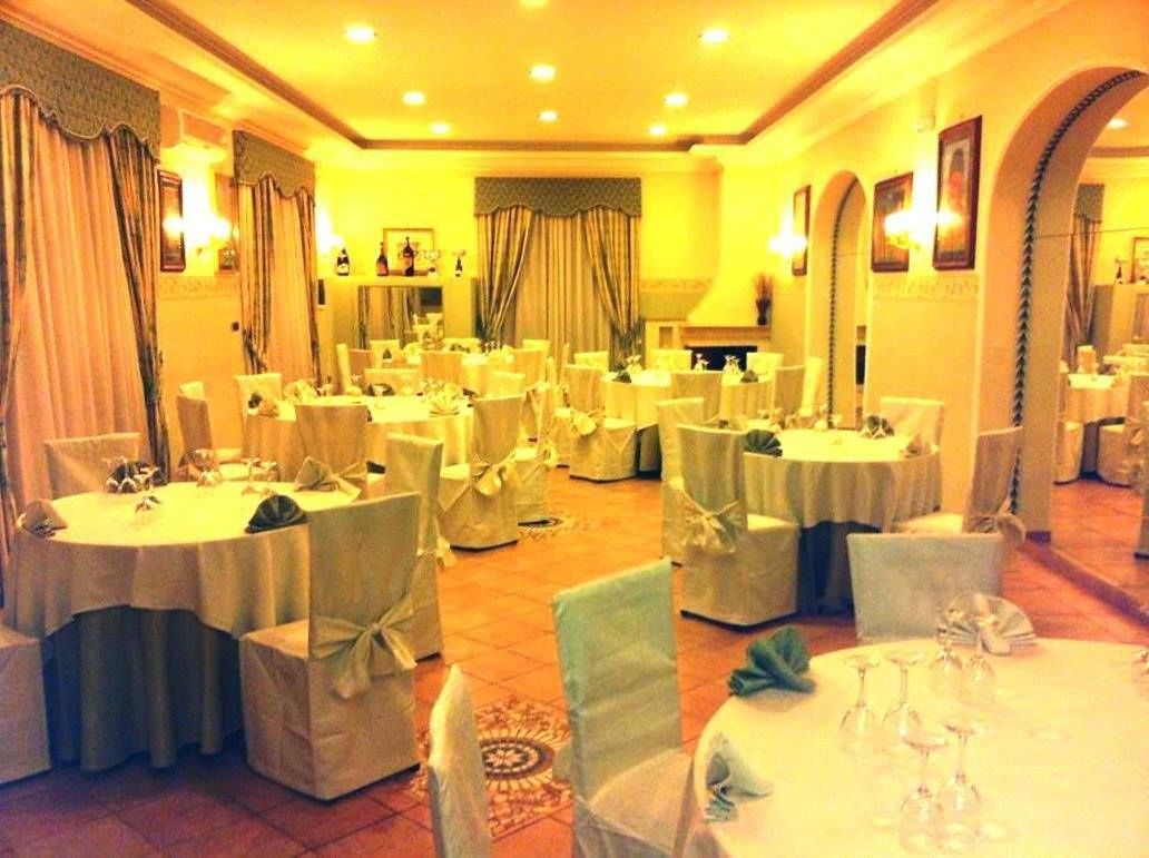 A banquet hall with round tables, chairs, and chandeliers.