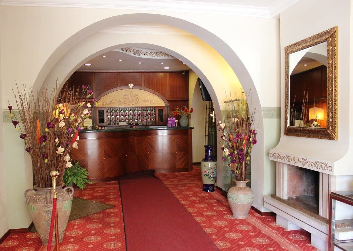 A hotel lobby with a reception desk, a red carpet, and a fireplace.