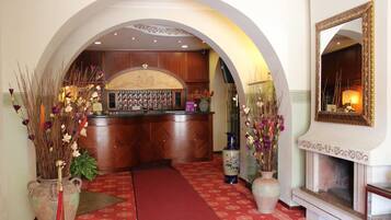 A hotel lobby with a reception desk, a red carpet, and a fireplace.