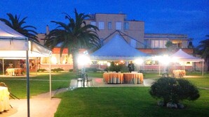 An outdoor event space with tables and chairs, tents, and a building in the background. - Hotel Parco dei Principi (Anzio)