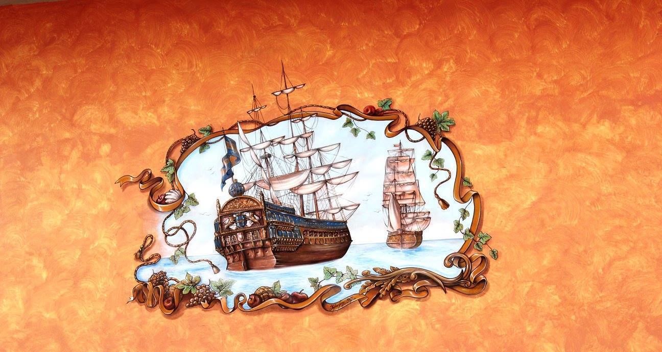 Una pared decorativa con temática marítima, que muestra un barco grande y un bote más pequeño.