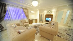 Een moderne woonkamer met twee beige banken, een salontafel en een televisie.