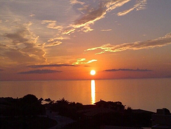 A sunset over a body of water with a silhouette of buildings in the foreground.