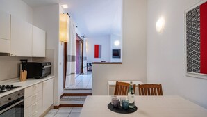 Una cocina moderna con armarios blancos, una estufa y un microondas. Hay un comedor con mesa y sillas, y una isla de cocina con un lavamanos.