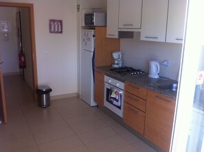 A compact kitchen with a refrigerator, microwave, stove, and a coffee maker.