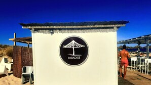 Um edifício à beira-mar com uma placa que diz "PARADISE" e um deck de madeira que o acessa.