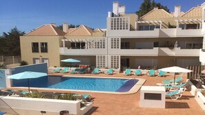 Um hotel com piscina, várias varandas e áreas de estar ao ar livre.