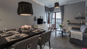 A modern living room with a dining area, a TV, and a balcony with a view.