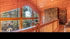 A wooden interior with large windows, a stone wall, and a bookshelf. - MOUNTAIN HOME--GOLD STAR WINNER!--A peaceful place to breathe in, breathe out... (Hot Springs Village)