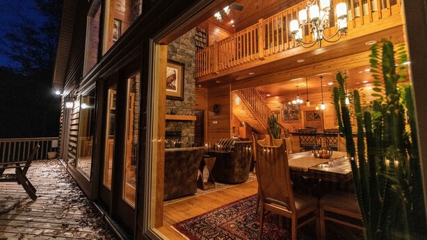 A cozy interior with a wooden staircase, a dining area with a table and chairs, and a balcony with a railing. - MOUNTAIN HOME--GOLD STAR WINNER!--A peaceful place to breathe in, breathe out... (Hot Springs Village)