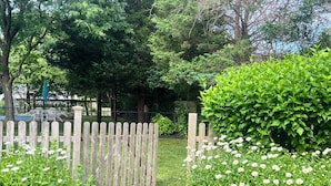 Un jardin avec une clôture en bois, des arbustes verts et des fleurs blanches.