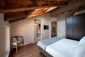 Ein Schlafzimmer mit Holzboden, einem Bett, einem Sessel und einem Kleiderschrank.