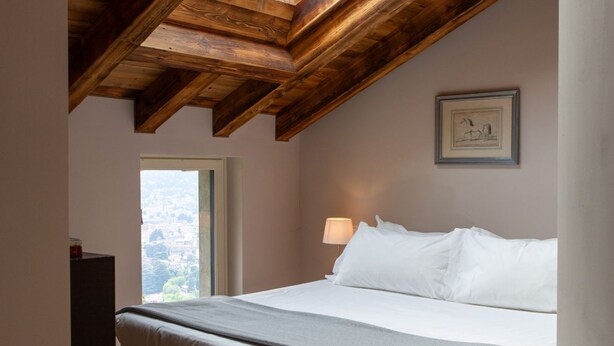 Ein Schlafzimmer mit Holzboden, einem Bett mit weißer Bettwäsche, einem Nachttisch mit Lampe und einem gerahmten Bild an der Wand.