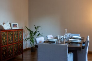 Een eetruimte met een tafel voor vier personen, een potplant en een decoratieve kast.