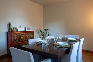 Een eetgedeelte met een donkerhouten tafel voor vier personen, omringd door lichtblauwe gestoffeerde stoelen.