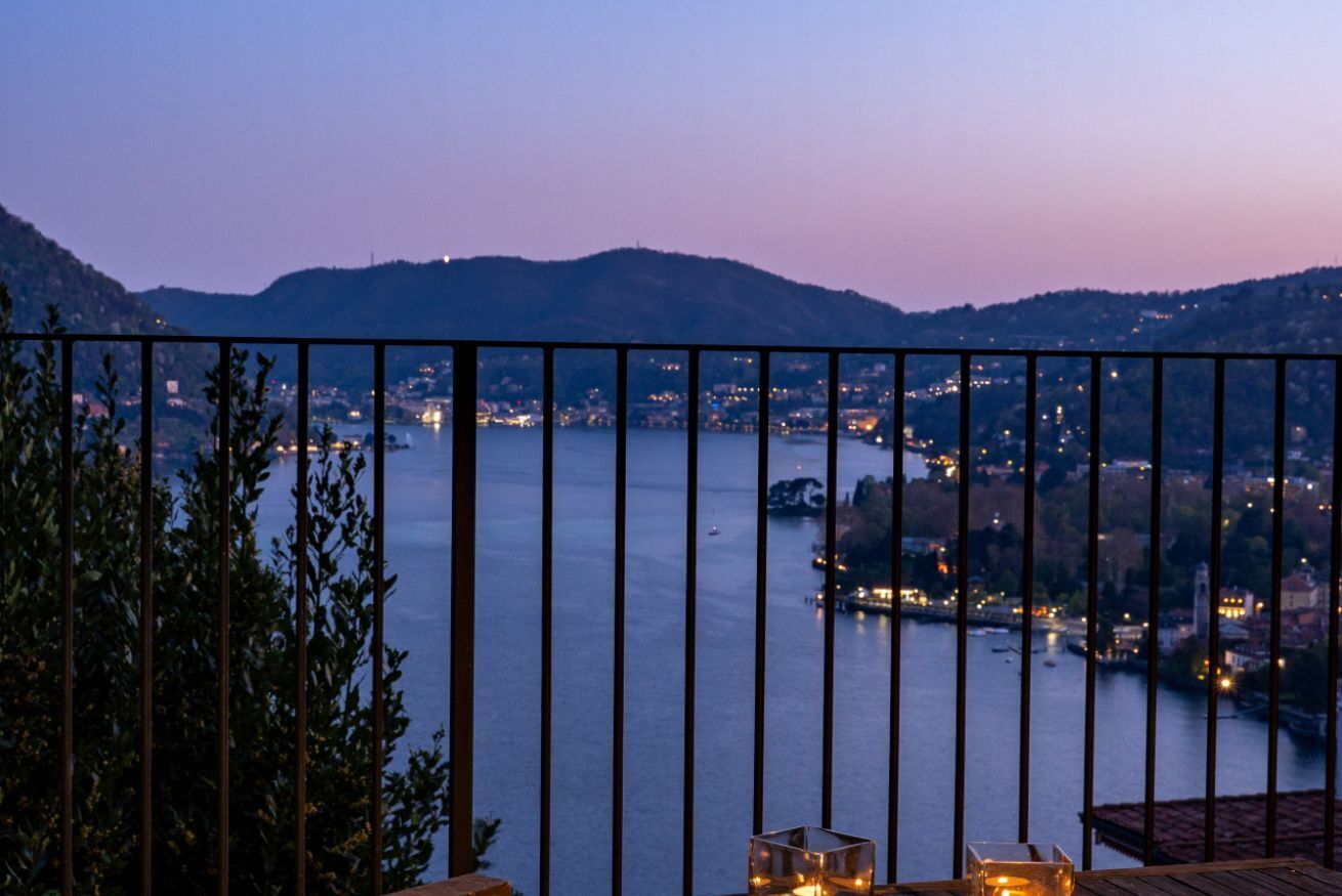 A balcony with a view of a lake and distant city lights.