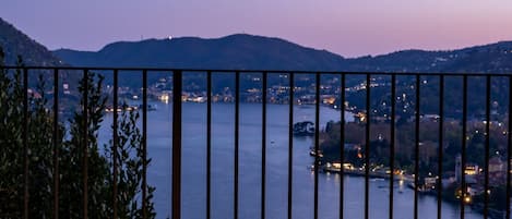 A balcony with a view of a lake and distant city lights.
