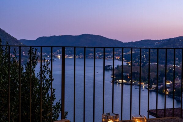 A balcony with a view of a lake and distant city lights.