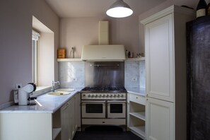 A kitchen with a stove, double oven, and a window.