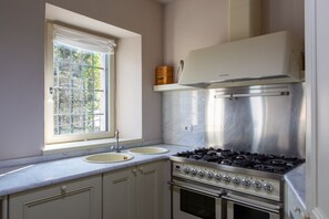 Una cucina con due lavandini, un fornello e una finestra vista alberi.