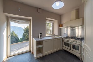 A kitchen with a stove, oven, and two windows with curtains. - Toldino House 4 min. by car to lake (Cernobbio)
