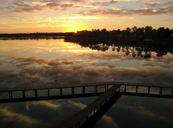 A sunset over a calm lake with a wooden pier extending into the water.
