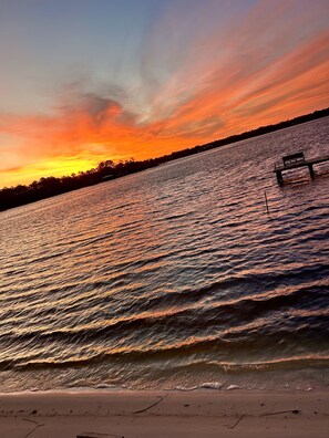 Un tramonto su un corpo d'acqua con una panchina sulla riva.