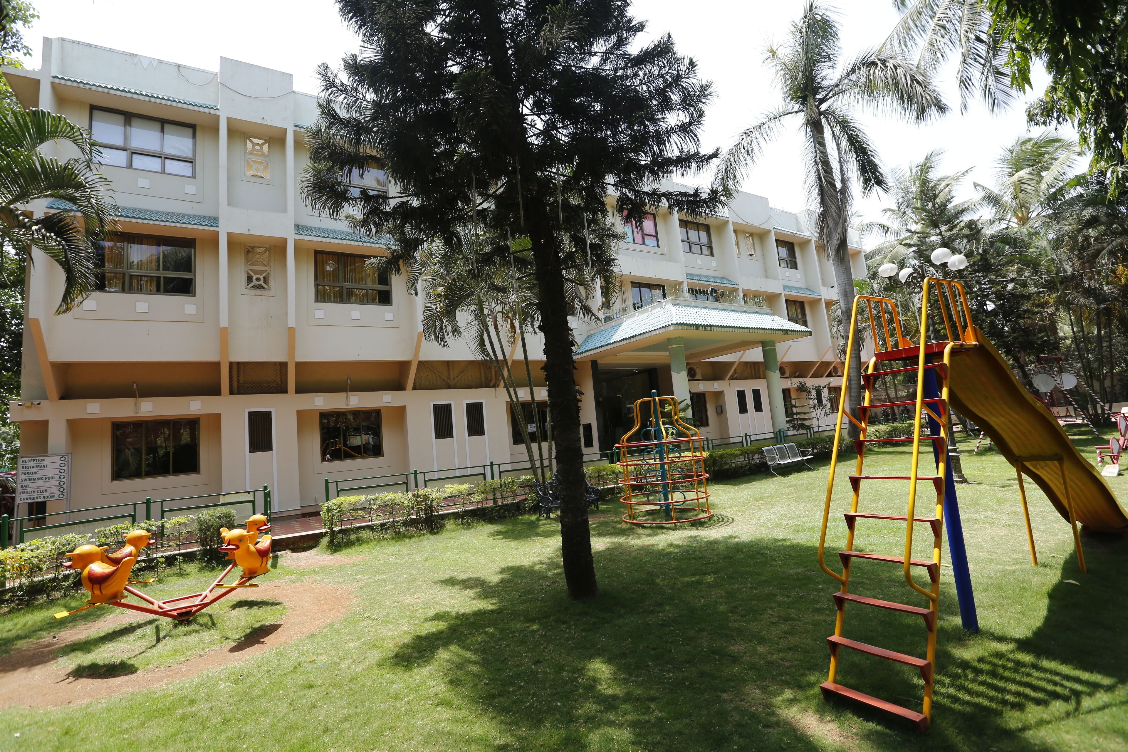 Un parque infantil con un tobogán y estructuras de escalada, rodeado por un edificio con múltiples ventanas y balcones.