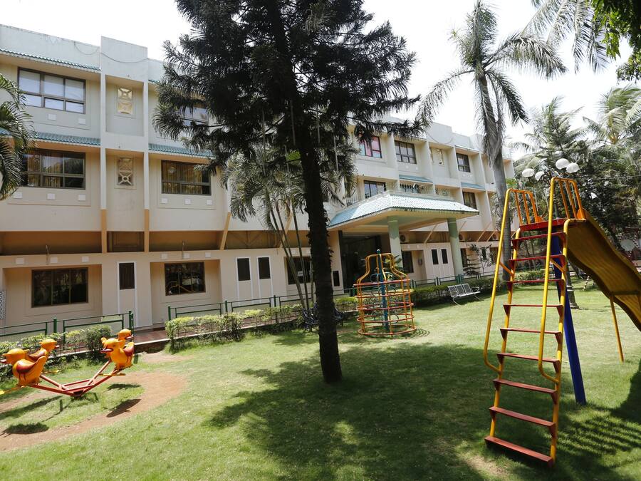 Un parque infantil con un tobogán y estructuras de escalada, rodeado por un edificio con múltiples ventanas y balcones.