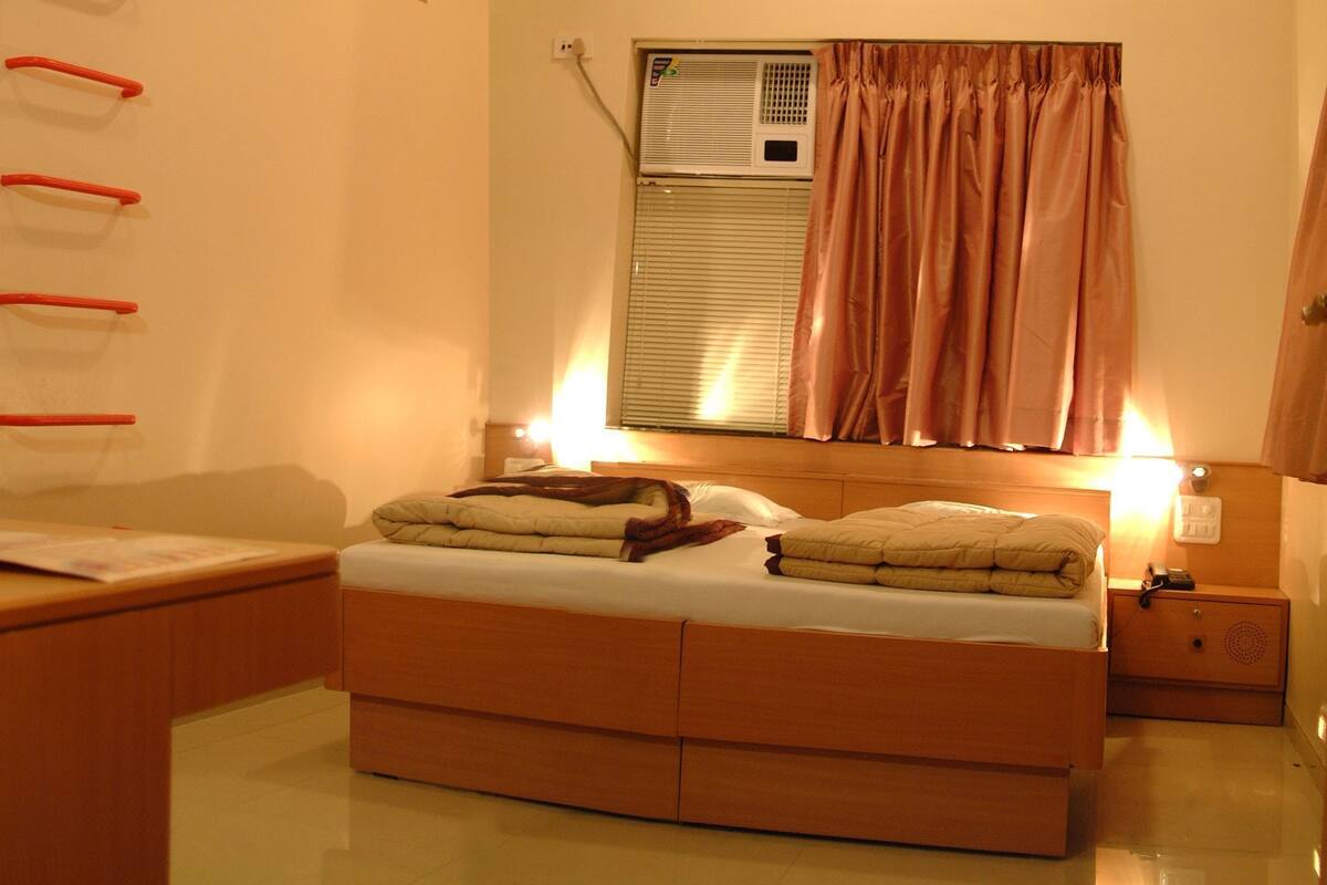 A bedroom with a bed, bedside table, and an air conditioning unit.