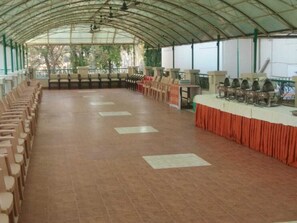 A covered outdoor area with rows of chairs and tables, likely for dining or events.