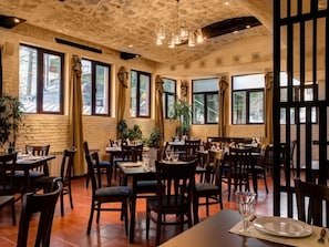 A restaurant with brick walls, large windows, and wooden tables and chairs. - 1 bed apartment in Borovets, 150m from the gondola, views down the valley (Borovets)
