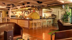 Eine Bar mit Holzsesseln, einer Theke mit Flaschen und einer Küche im Hintergrund.